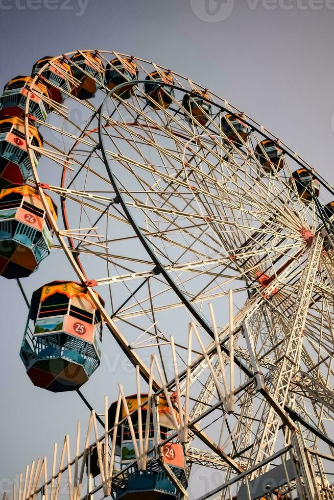 fechar-se do multicolorido gigante roda durante dussehra mela dentro Délhi, Índia. inferior Visão do gigante roda balanço. roda gigante com colorida cabines durante dia tempo. foto