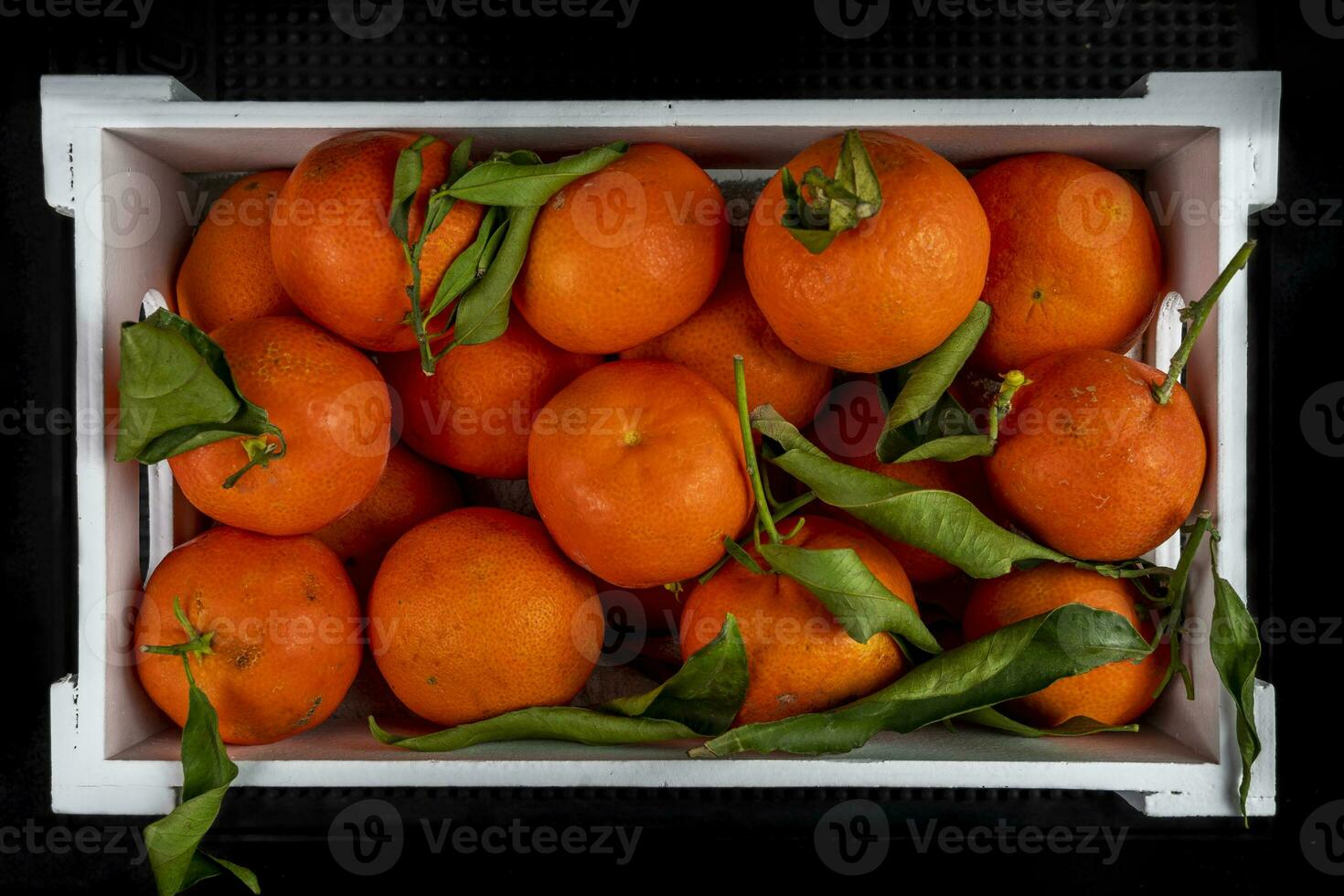 de madeira caixa cheio do tangerinas com verde folhas foto