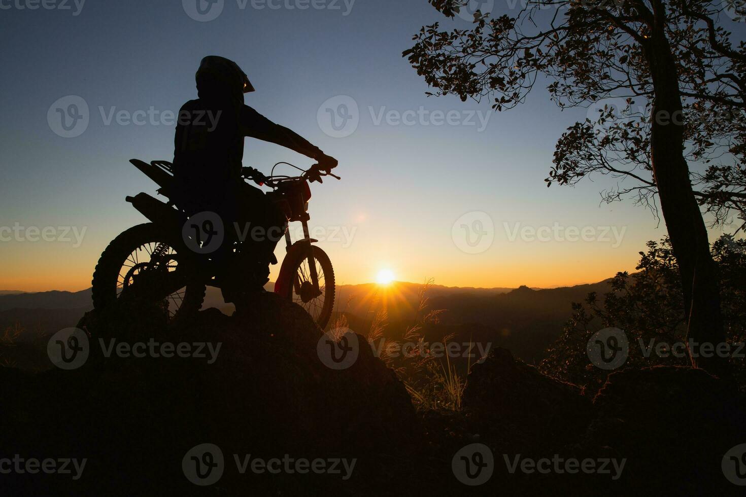 homem com motocross bicicleta contra lindo luzes, silhueta do uma homem com motocross motocicleta em topo do Rocha Alto montanha às lindo pôr do sol, enduro motocicleta viagem conceito. foto