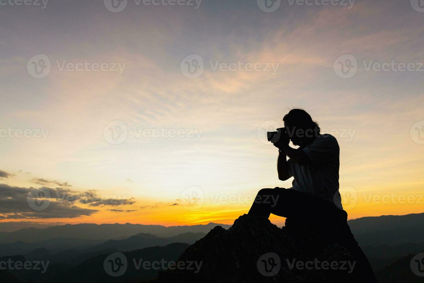 silhueta do uma fotógrafo em topo do uma montanha às pôr do sol foto