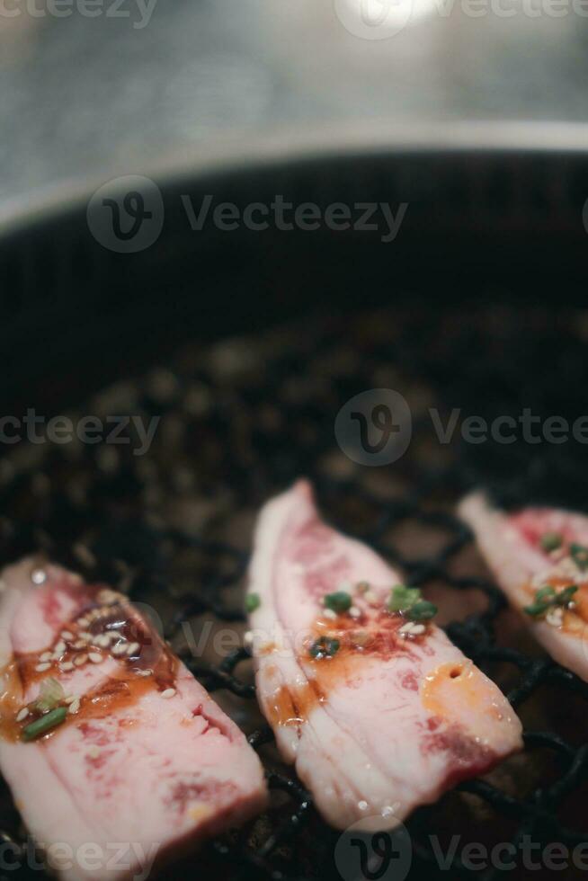 cru carne fatia para churrasco sobre carvão em fogão dentro restaurante, japonês Comida foto