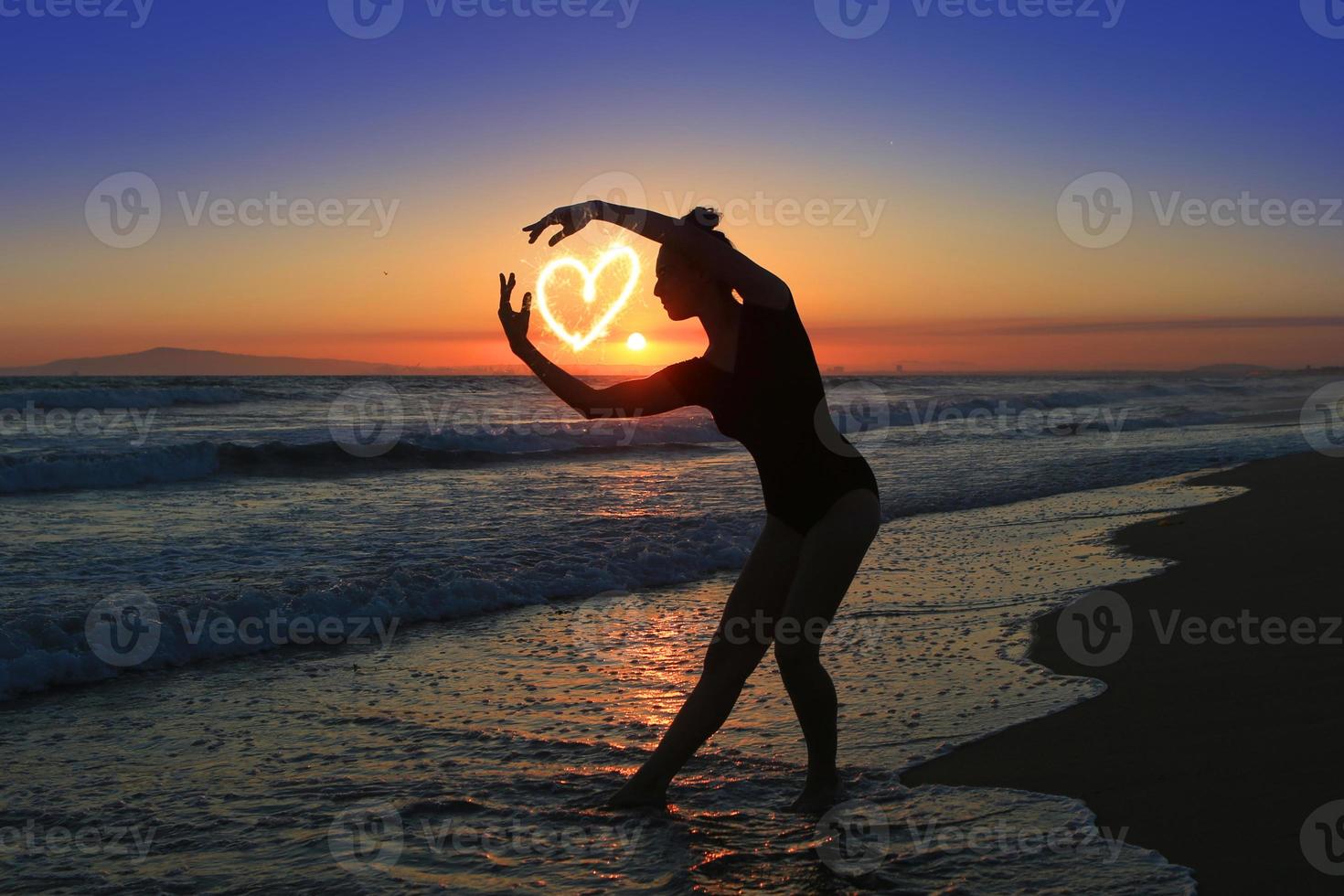 jovem dançarina habilidosa na praia durante o pôr do sol foto