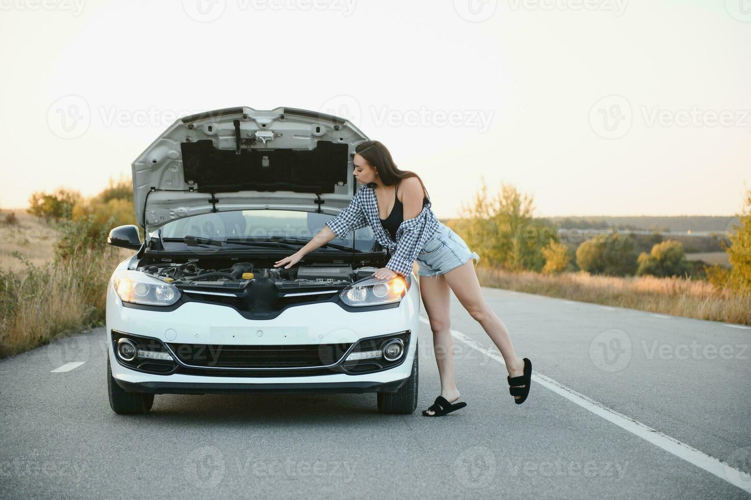 lindo fino menina dentro camisa e calção parece dentro aberto carro de capuz em uma estrada foto