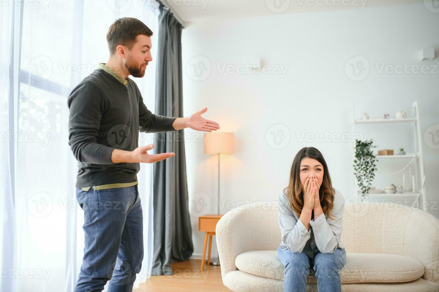 emocional homem gesticulando e gritando às dele esposa, jovem casal tendo brigar às lar. doméstico Abuso conceito foto