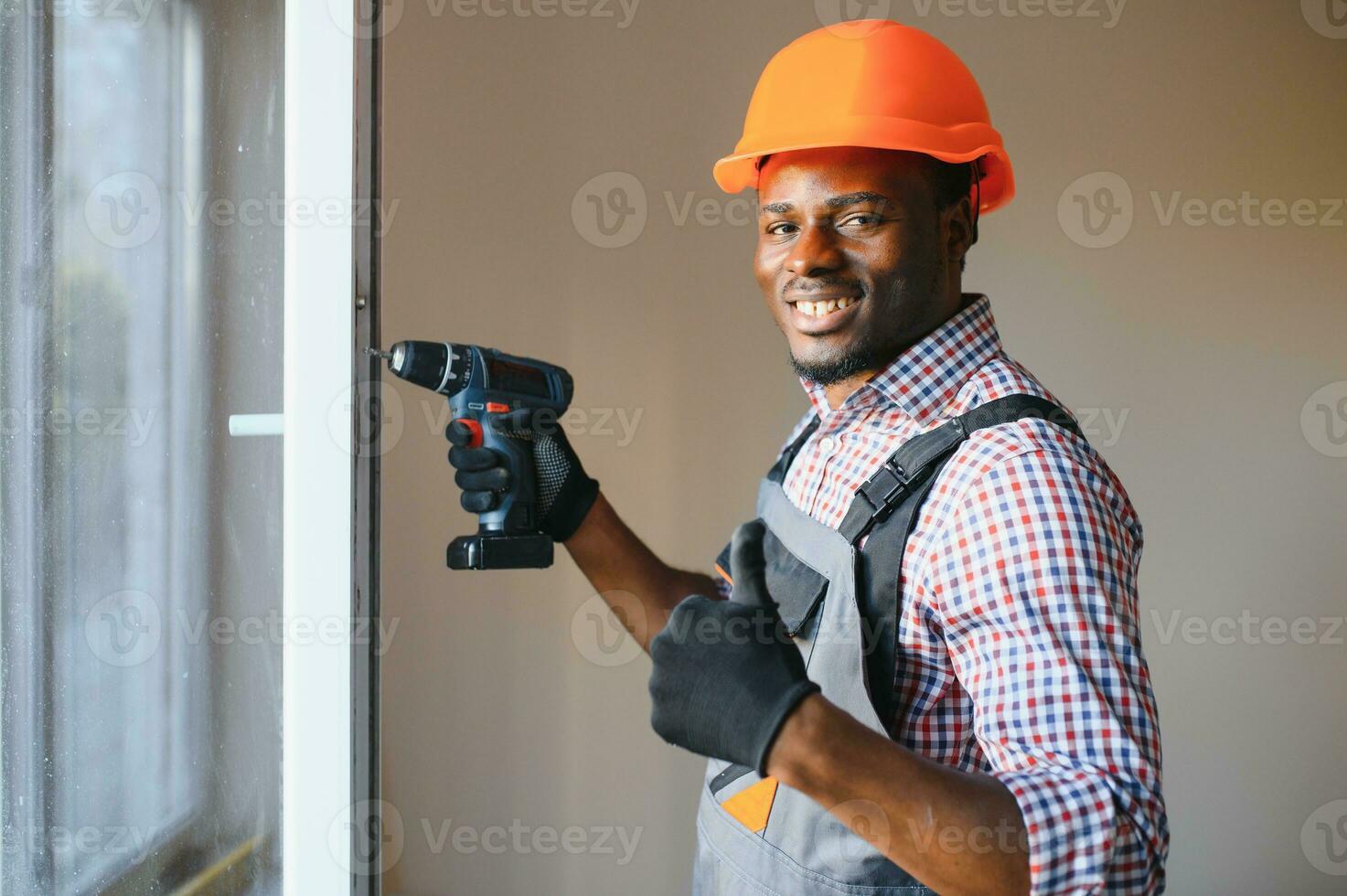 bonito jovem africano americano homem instalando baía janela dentro Novo casa construção local foto