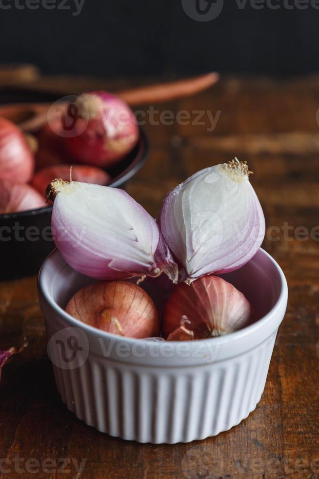 cebola vermelha fresca em uma tigela na mesa de madeira. foto