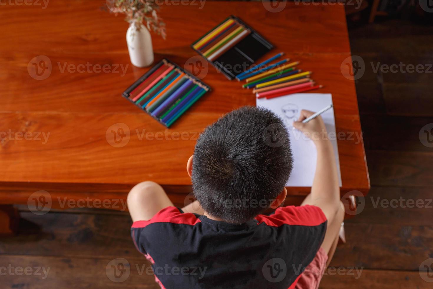 um menino sentado em sua casa desenhando e pintando. foto