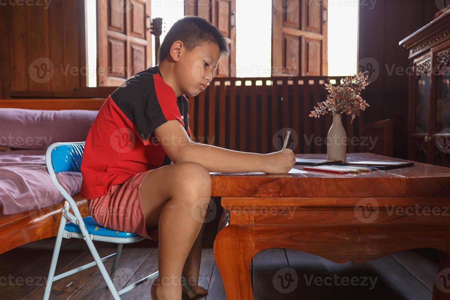 um menino sentado em sua casa desenhando e pintando. foto