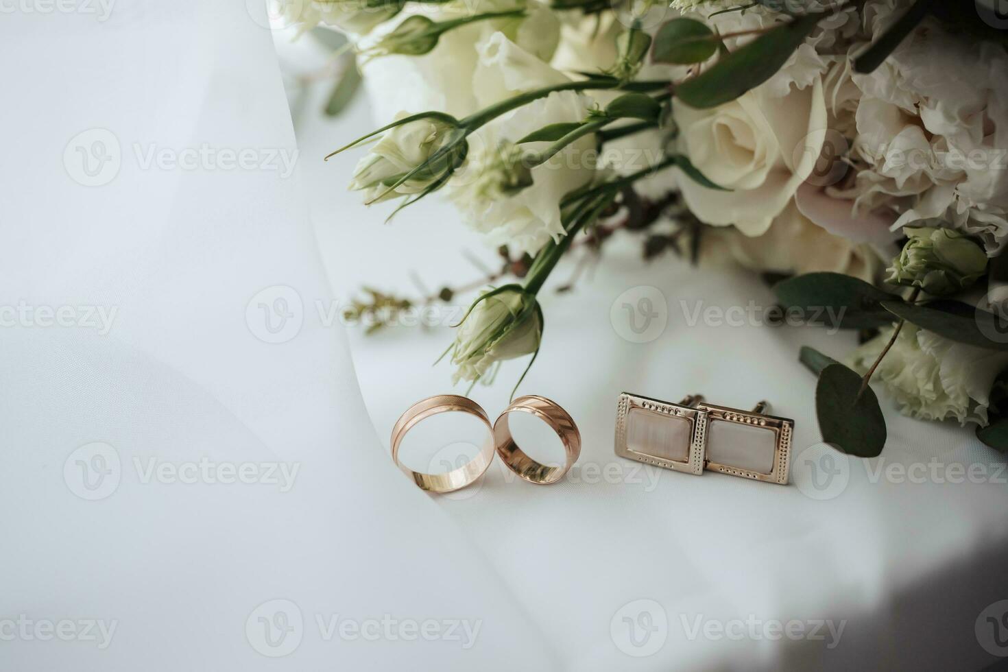 Rosa e branco flores e dois ouro Casamento argolas e abotoaduras em uma branco fundo. Casamento acessórios foto