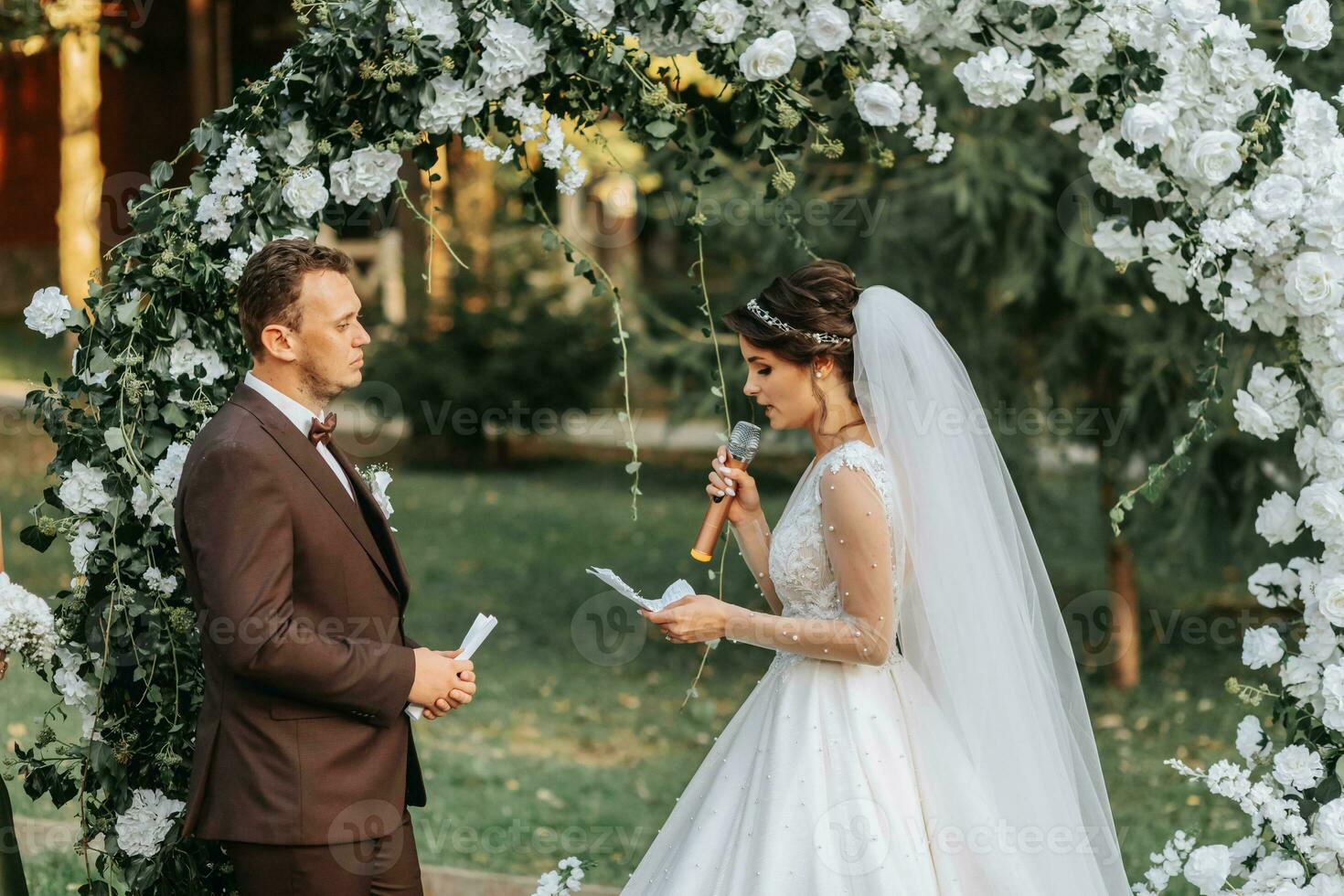 lindo Casamento casal em a Casamento outono cerimônia. a volta arco é decorado com branco flores foto