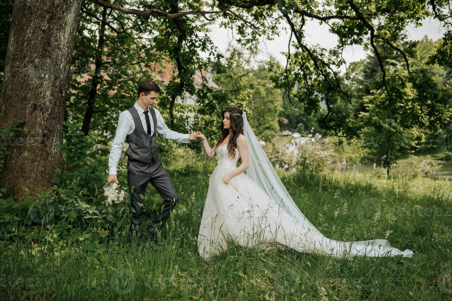 feliz jovem casal. a noivo leva dela de a mão e conduz dela lá em cima. Casamento ramalhete. Primavera Casamento foto