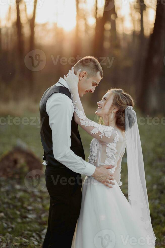 Casamento foto. a noiva e noivo estão caminhando dentro a floresta. a noivo abraços a ombros do dele amado. grandes Casamento vestir. uma casal dentro amor entre alta árvores outono luz solar. foto