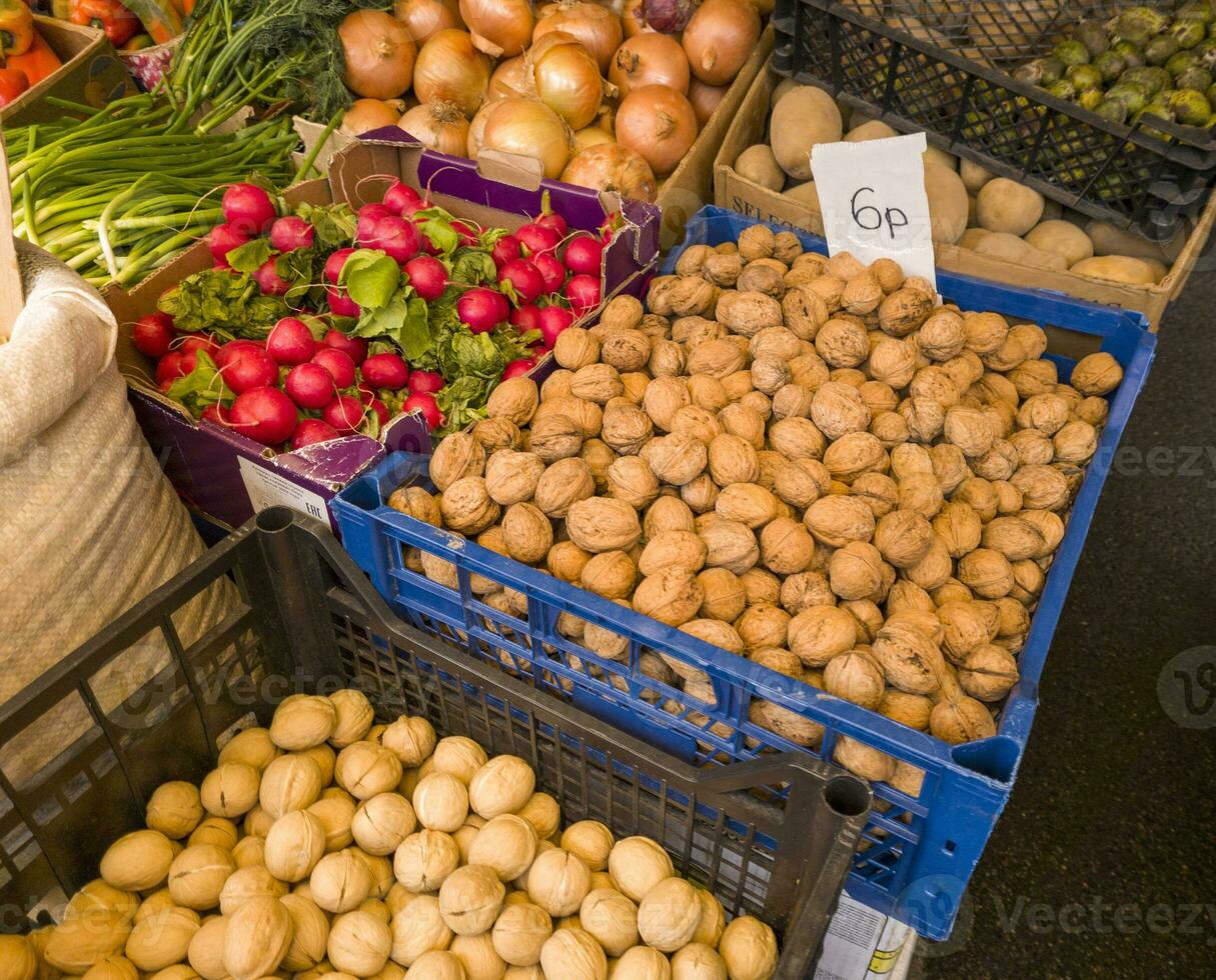 uma variedade do fresco frutas, sementes, nozes e legumes em exibição às a mercado. Comida foto