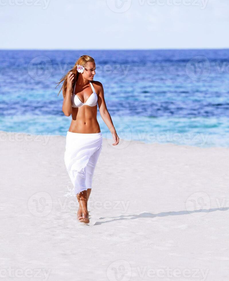 quente menina caminhando em a de praia foto