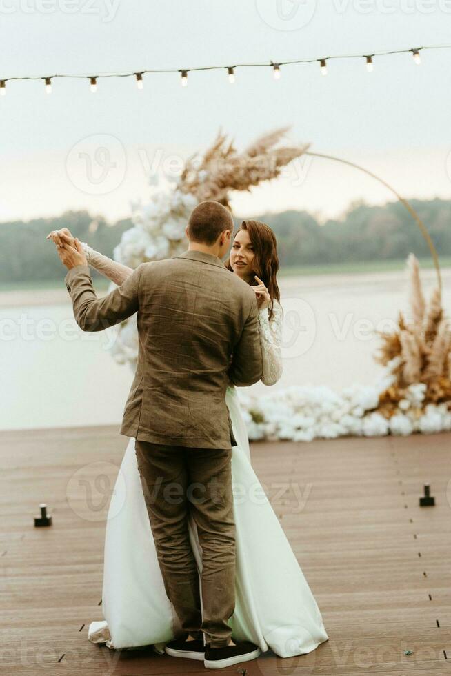 a primeiro Casamento dança do a noiva e noivo em a cais perto a rio foto