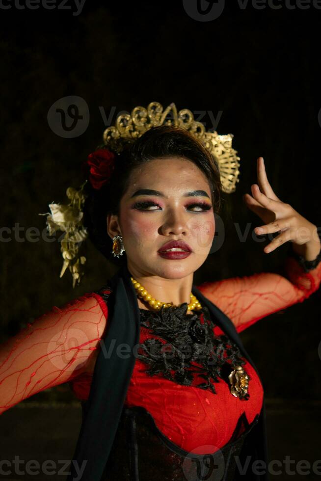 fechar acima do a indonésio mulher dentro uma balinesa dançarino traje posando muito belas às noite foto