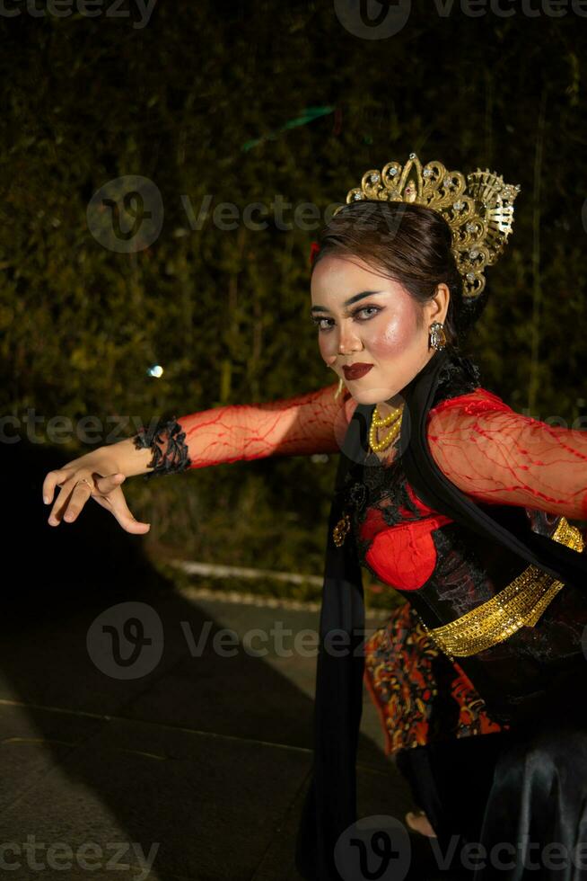 a ásia dançarino dentro uma vermelho traje poses muito flexível em uma etapa foto