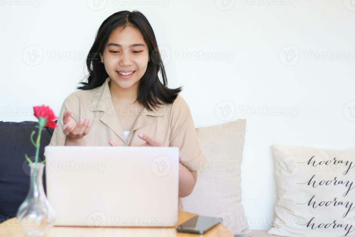 animado ásia mulher usando computador portátil Faz conectados encontro com levantando Palmeiras apresentando gesto sentado em sofá dentro de casa vestindo casual à moda foto