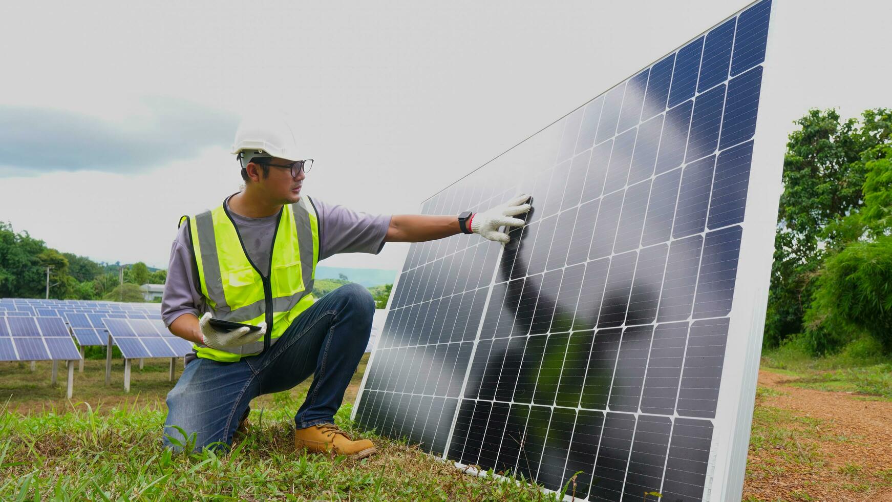 ásia homem engenheiro usando digital tábua mantendo solar célula painéis trabalhando ao ar livre em ecológico solar Fazenda construção. foto