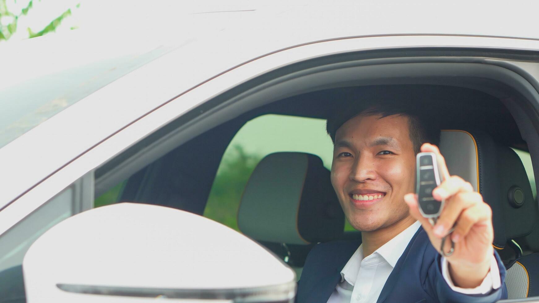 jovem ásia homem de negocios mostrando uma carro chave dentro dele Novo elétrico veículo. ev carro. foto