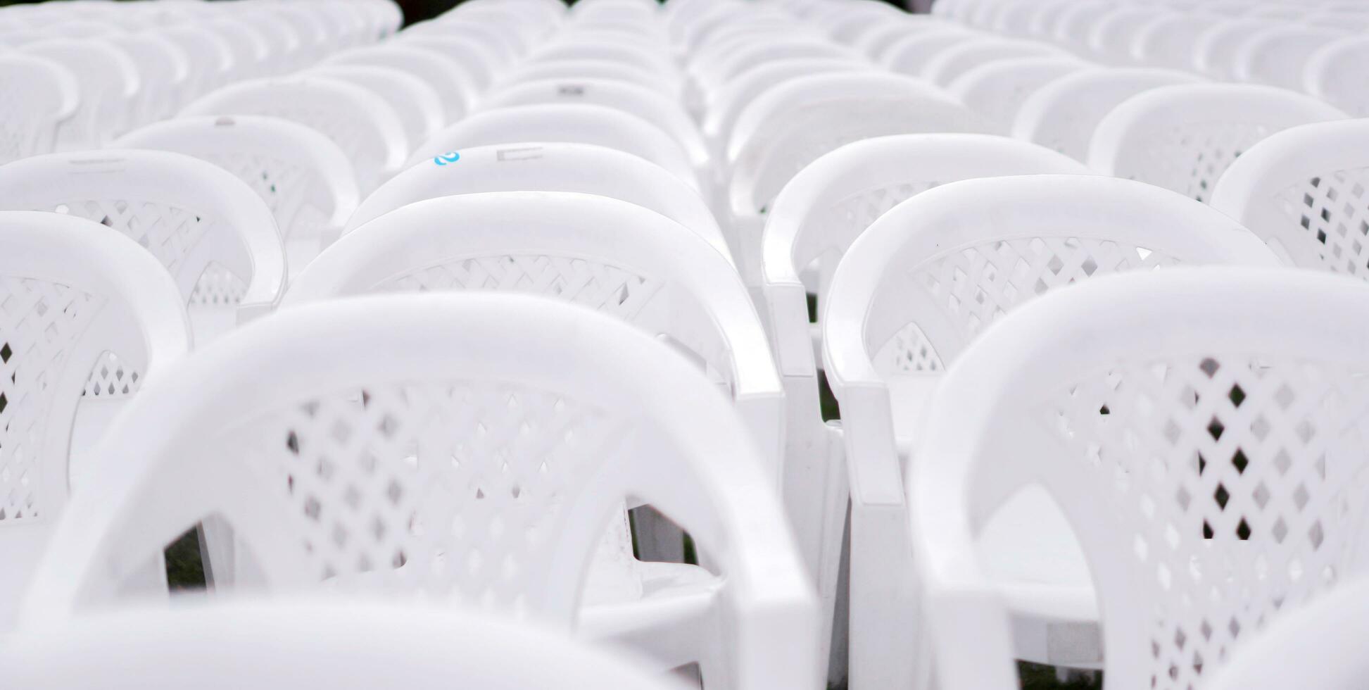fechar-se e colheita branco plástico cadeiras colocar em forrado dentro linhas para alunos dentro a graduação cerimônia. foto