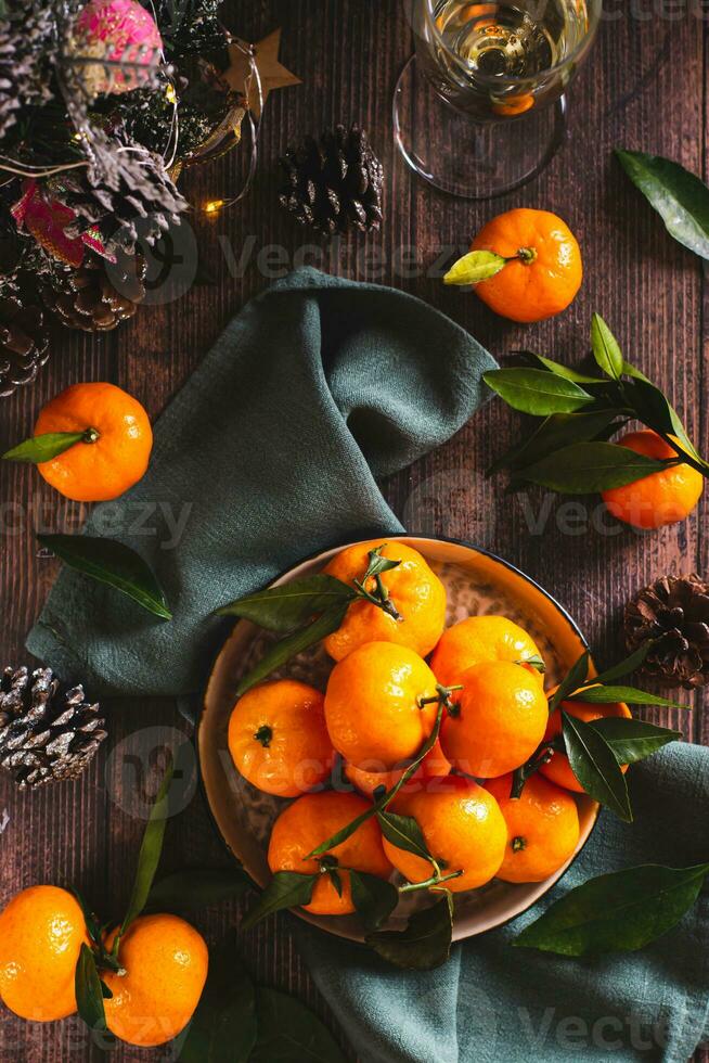 fresco tangerinas com folhas em uma prato em a Natal mesa topo e vertical Visão foto