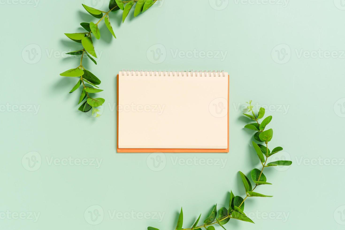 foto plana leiga criativa da mesa do espaço de trabalho. mesa de escritório de vista superior com maquete aberta, cadernos em branco e planta sobre fundo de cor verde pastel. vista superior com simulação de fotografia de espaço de cópia.