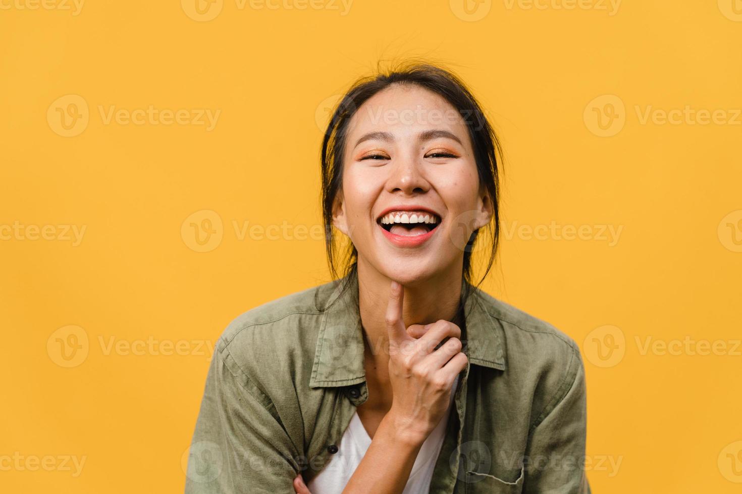 jovem asiática com expressão positiva, sorriso largo, vestida com roupas casuais e olhando para a câmera sobre fundo amarelo. feliz adorável feliz mulher alegra sucesso. conceito de expressão facial. foto
