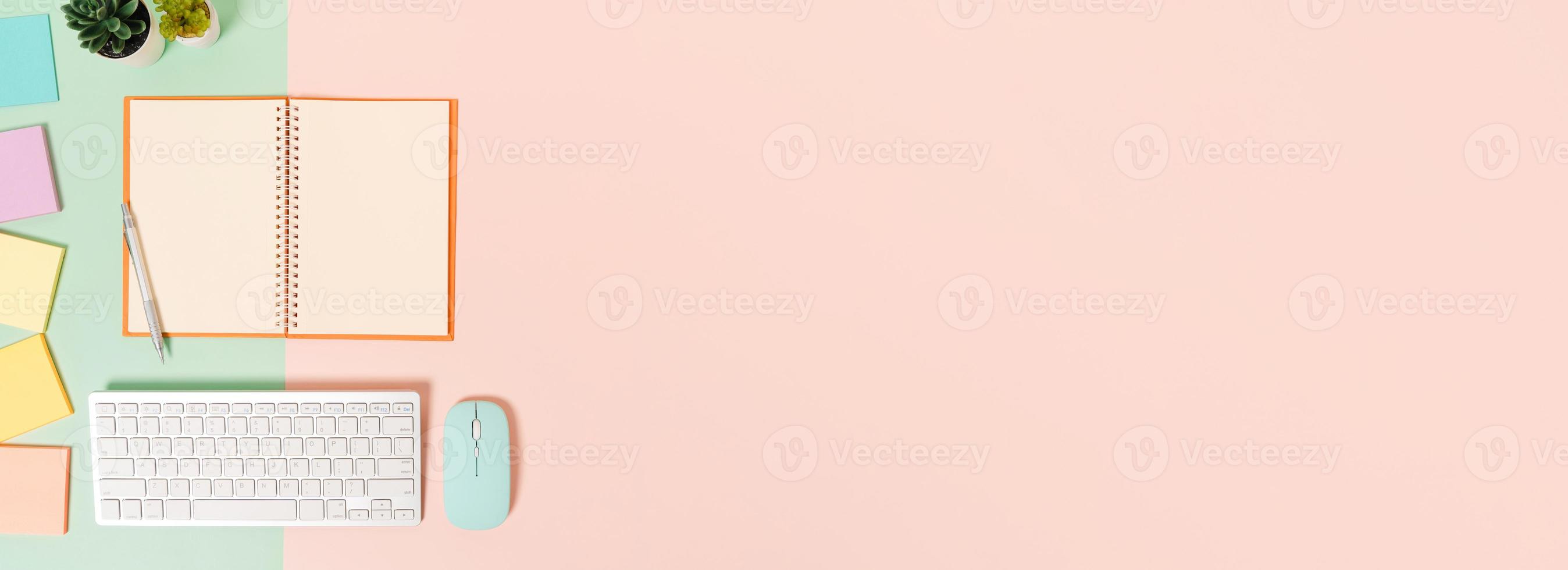 foto plana leiga criativa da mesa do espaço de trabalho. mesa de escritório de vista superior com teclado, mouse e caderno preto de maquete aberta sobre fundo de cor rosa verde pastel. vista superior simulada com fotografia do espaço da cópia.