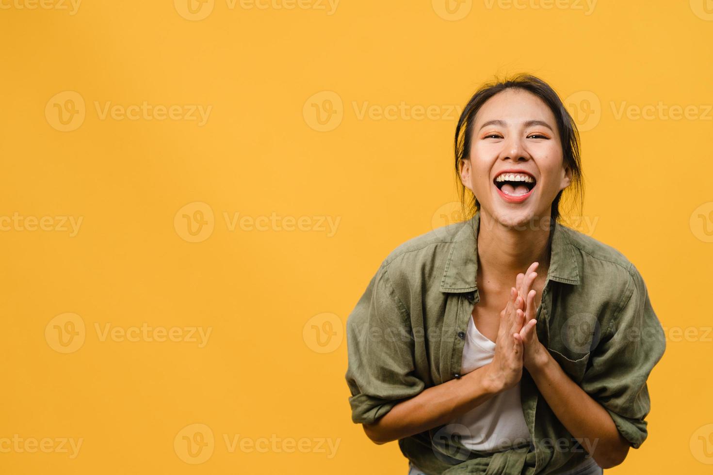 jovem asiática com expressão positiva, sorriso largo, vestida com roupas casuais e olhando para a câmera sobre fundo amarelo. feliz adorável feliz mulher alegra sucesso. conceito de expressão facial. foto