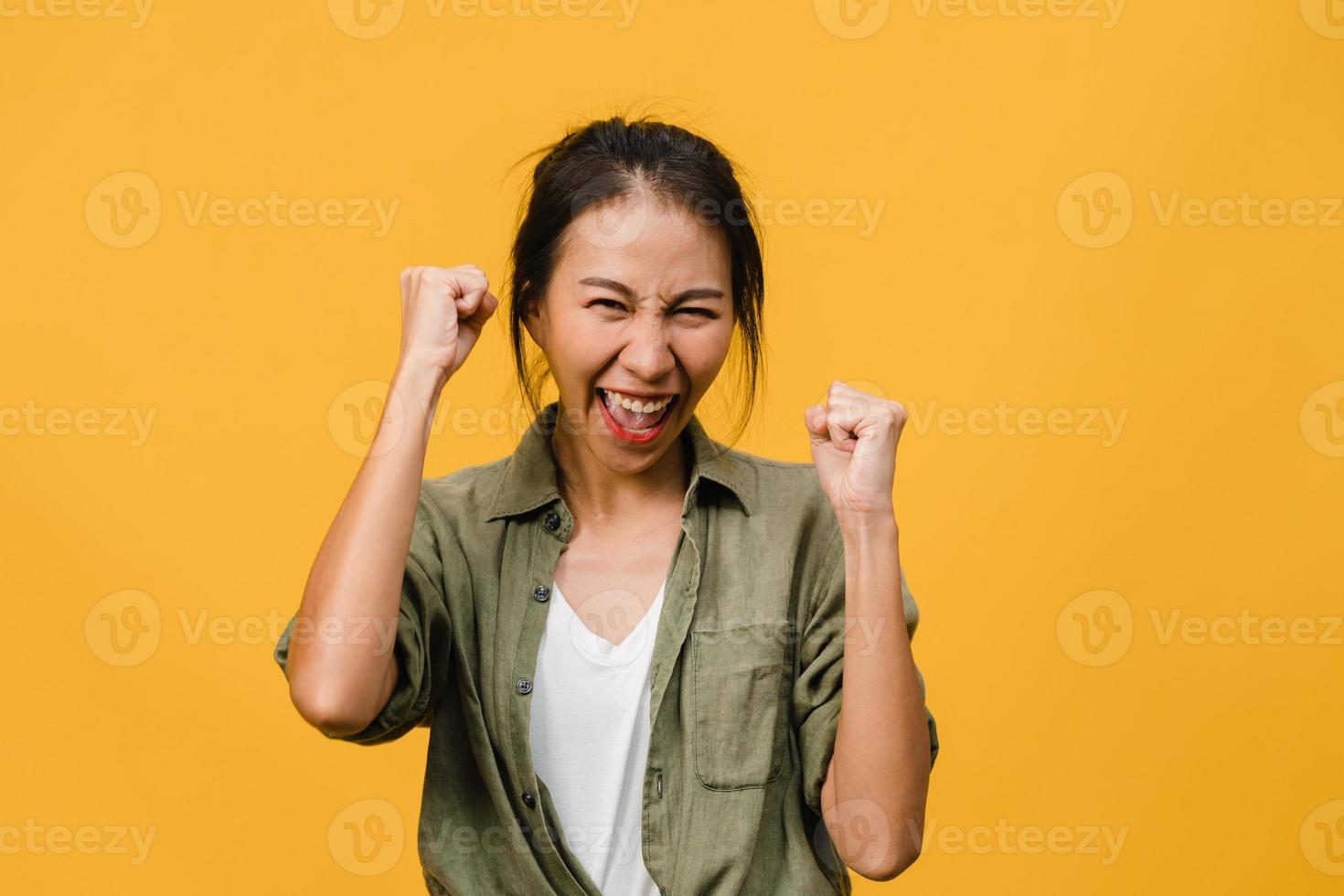jovem asiática com expressão positiva, alegre e emocionante, vestida com um pano casual e olha para a câmera sobre fundo amarelo. feliz adorável feliz mulher alegra sucesso. conceito de expressão facial. foto