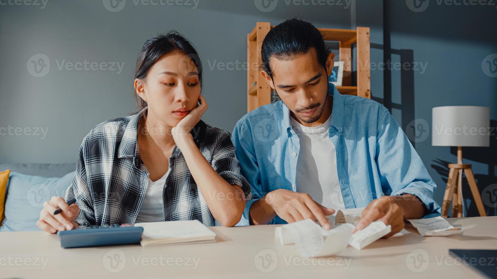 O homem e a mulher do casal asiático de estresse usam a calculadora para calcular o orçamento familiar, as dívidas, as despesas mensais durante a crise econômica financeira em casa. problemas de dinheiro do casamento, conceito de planejamento de orçamento familiar. foto