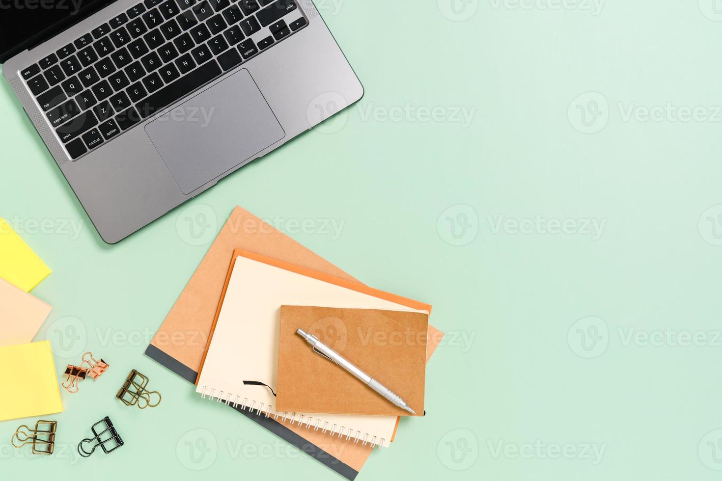 foto plana leiga criativa da mesa do espaço de trabalho. mesa de escritório de vista superior com laptop, xícara de café e caderno preto de maquete aberta sobre fundo de cor verde pastel. vista superior simulada com fotografia do espaço da cópia.