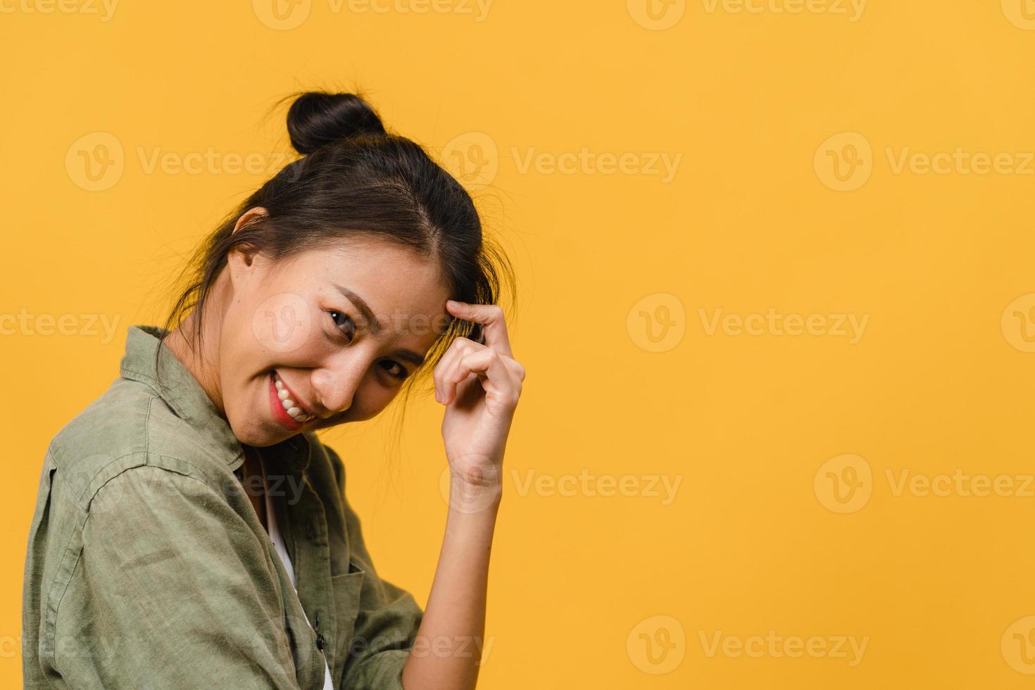 jovem asiática com expressão positiva, sorriso largo, vestida com roupas casuais e olhando para a câmera sobre fundo amarelo. feliz adorável feliz mulher alegra sucesso. conceito de expressão facial. foto