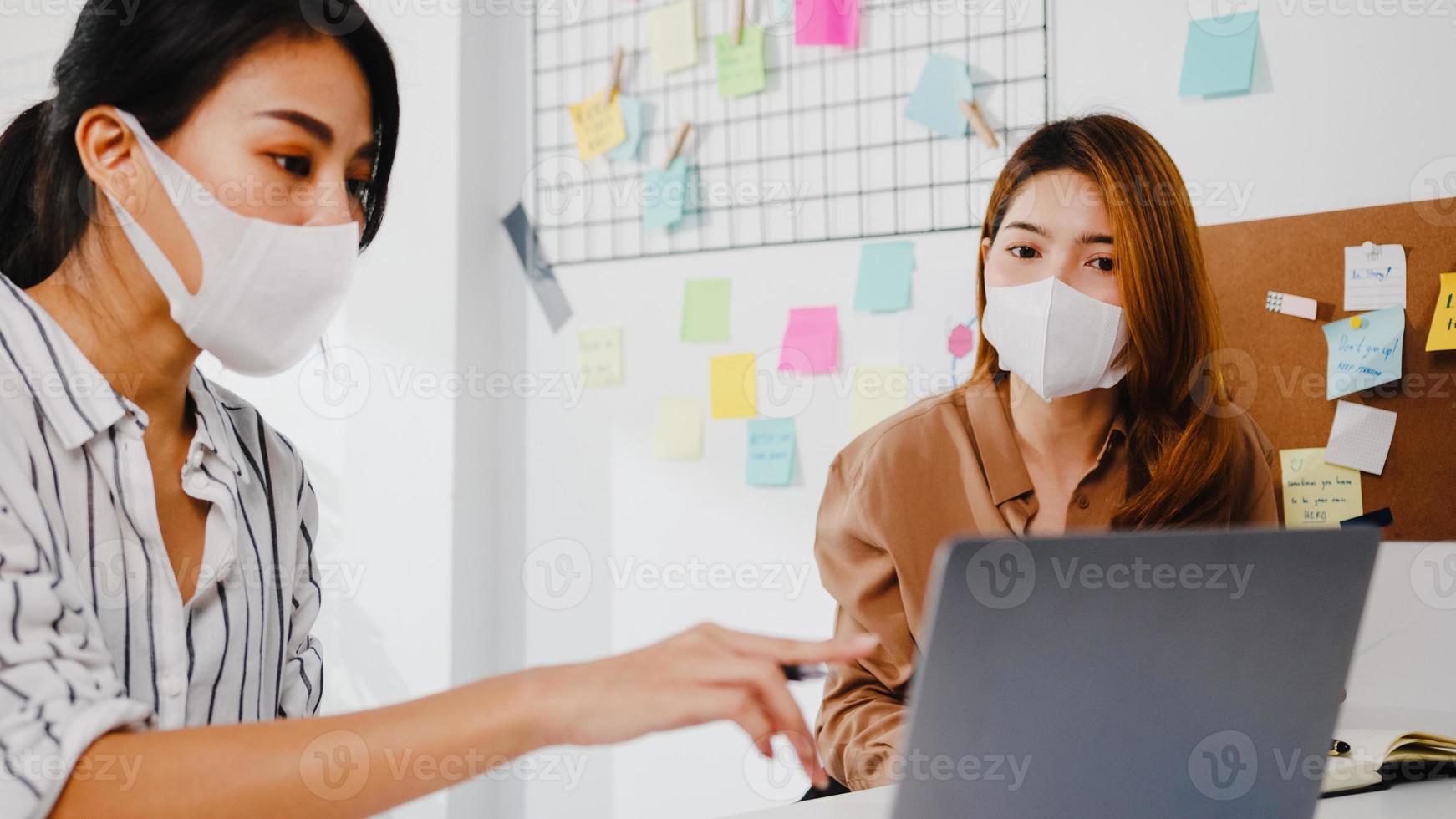 empresários asiáticos usando apresentação de computador, reunindo-se para debater ideias sobre novos colegas de projeto e usando máscara protetora no novo escritório normal. estilo de vida e trabalho após coronavírus. foto