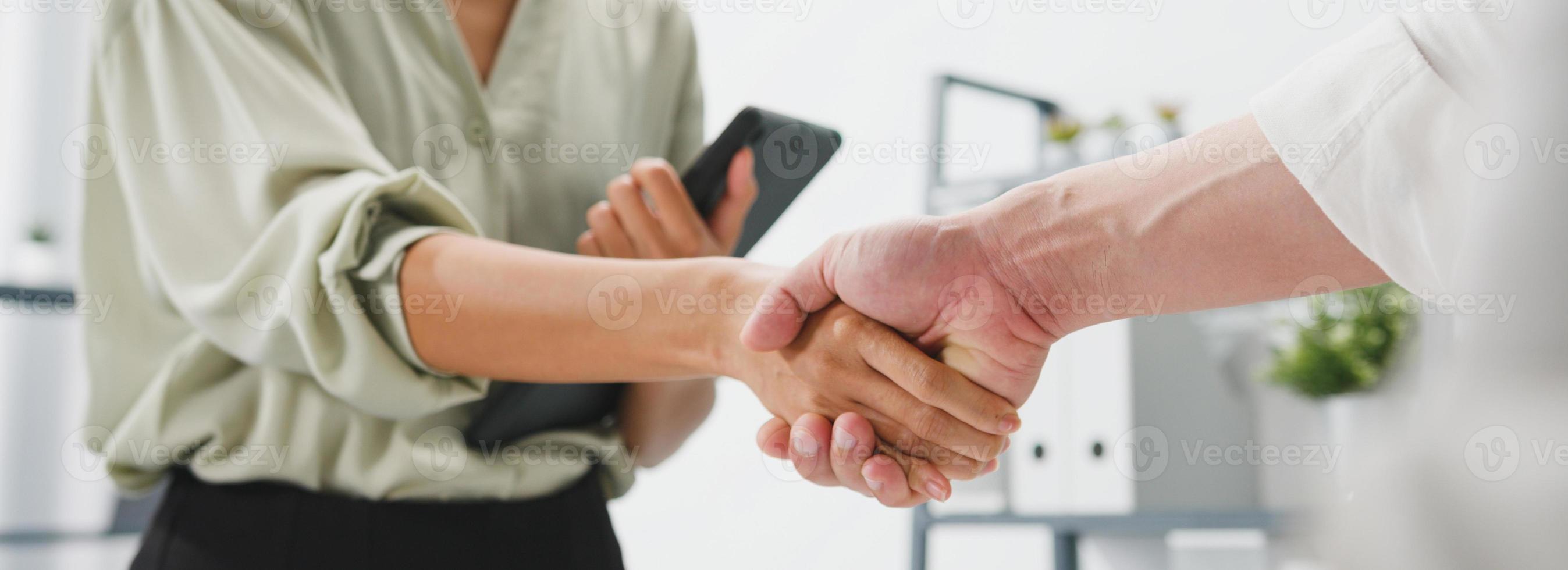 jovens criativos em smart casual wear discutindo negócios, apertando as mãos no escritório. cooperação de parceiros, conceito de trabalho em equipe do colega de trabalho. fundo de banner panorâmico com espaço de cópia. foto