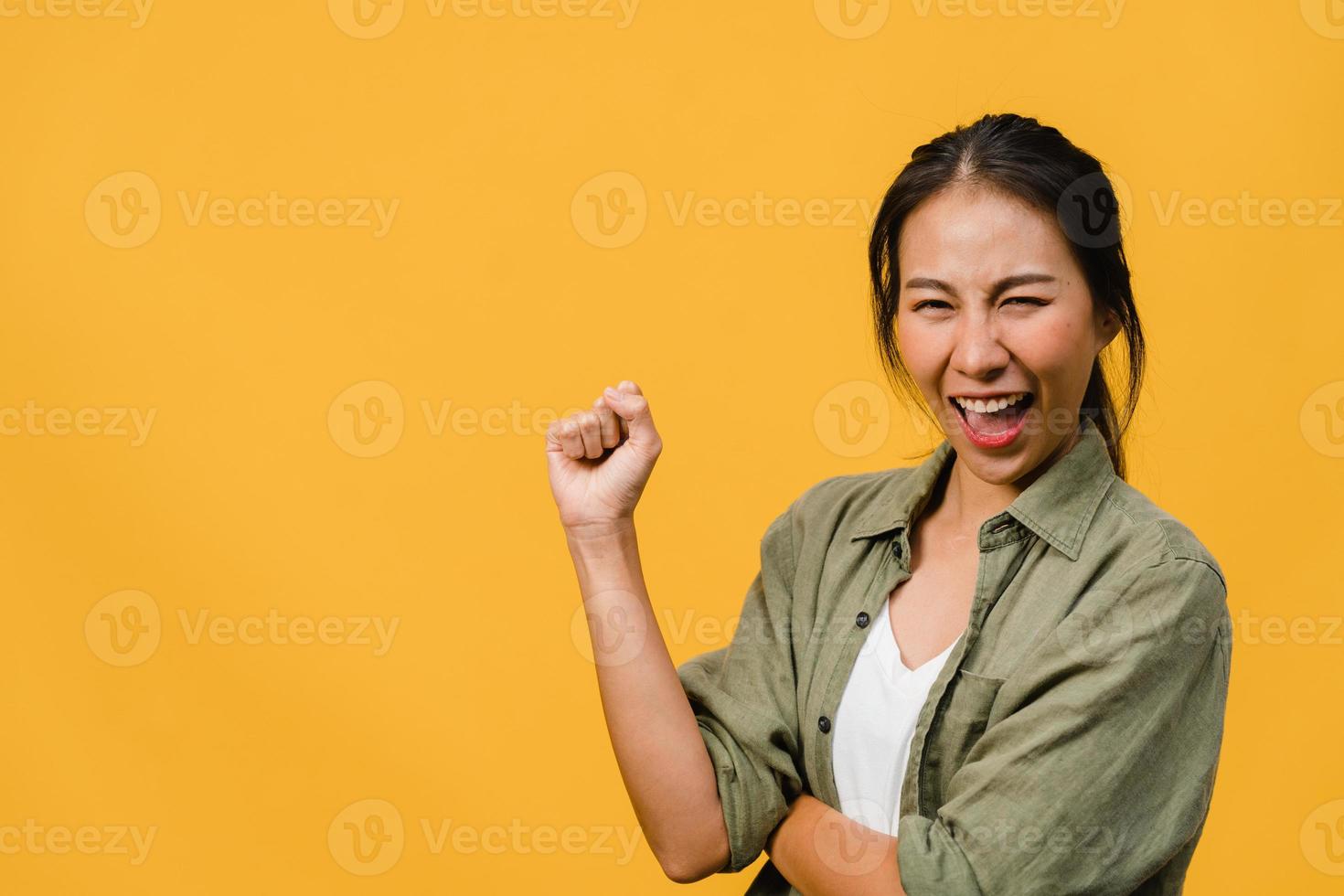 jovem asiática com expressão positiva, alegre e emocionante, vestida com um pano casual e olha para a câmera sobre fundo amarelo. feliz adorável feliz mulher alegra sucesso. conceito de expressão facial. foto