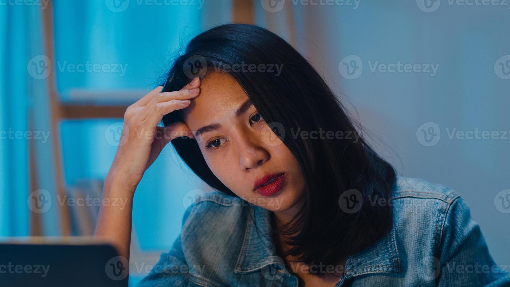 milenar jovem empresária chinesa trabalhando tarde da noite estressada com um problema de pesquisa de projeto no laptop na sala de estar em uma casa moderna. conceito de síndrome de burnout ocupacional de povos da Ásia. foto