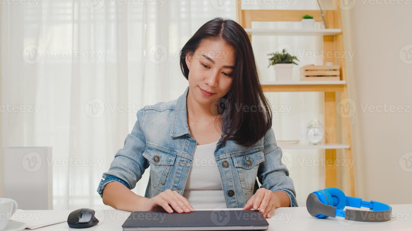 retrato de freelance smart business mulheres casual wear usando laptop, trabalhando no local de trabalho, na sala de estar em casa. feliz jovem asiática relaxar sentado na mesa de pesquisa e trabalhar na internet. foto