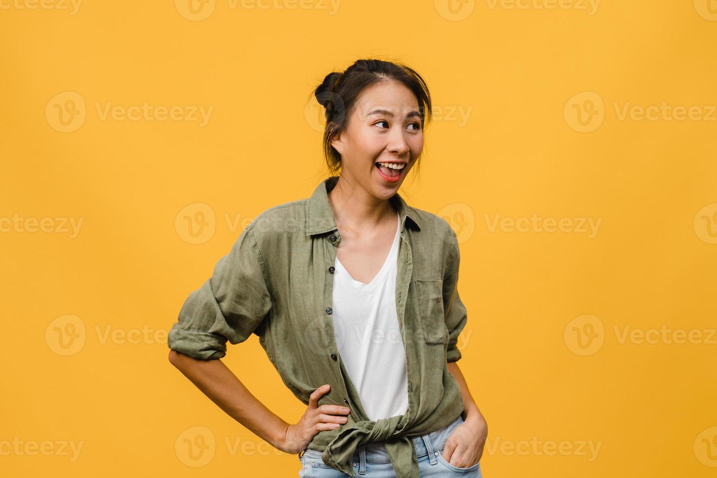 retrato de jovem asiática com expressão positiva, sorriso amplo, vestido com roupas casuais sobre fundo amarelo. feliz adorável feliz mulher alegra sucesso. conceito de expressão facial. foto