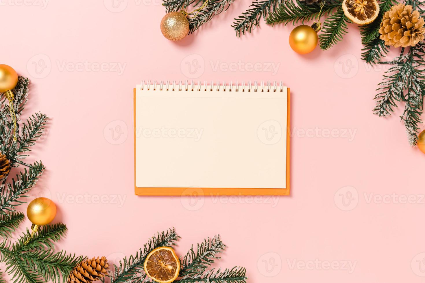 mínima criativa plana lay de composição tradicional de natal de inverno e temporada de férias de ano novo. vista superior caderno preto de maquete aberta para texto em fundo rosa. mock up e cópia da fotografia do espaço. foto