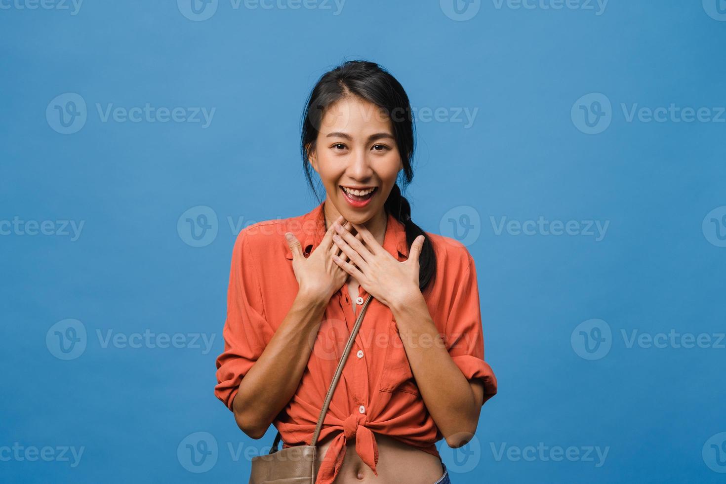 jovem asiática com expressão positiva, sorriso largo, vestida com roupas casuais e olhando para a câmera sobre fundo azul. feliz adorável feliz mulher alegra sucesso. conceito de expressão facial. foto