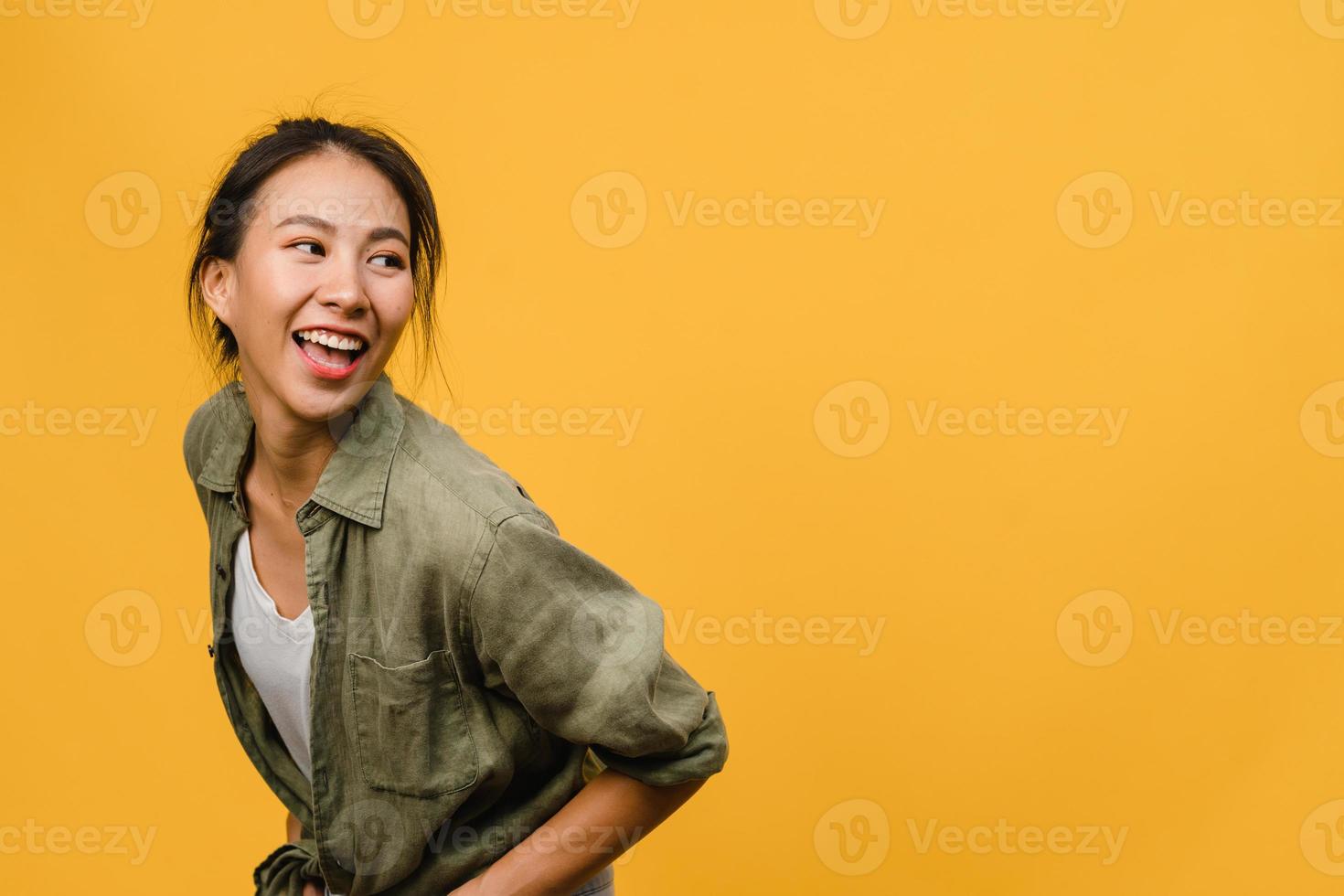 retrato de jovem asiática com expressão positiva, sorriso amplo, vestido com roupas casuais sobre fundo amarelo. feliz adorável feliz mulher alegra sucesso. conceito de expressão facial. foto