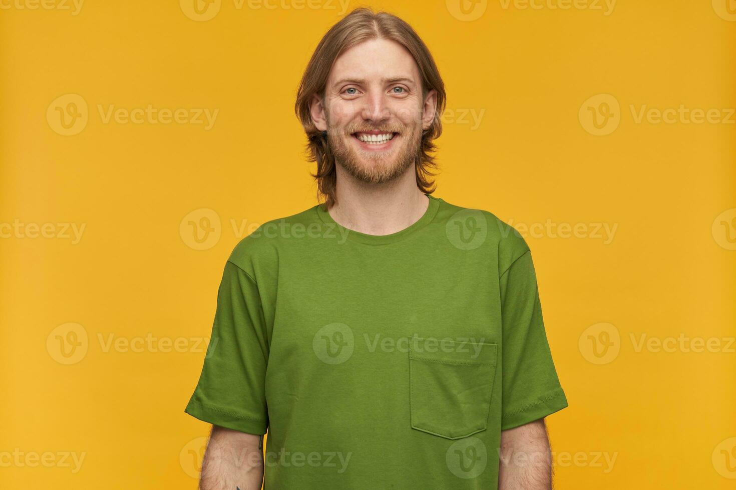 retrato do bonito, alegre masculino com loiro Penteado e barba. vestindo verde camiseta. amplamente sorridente. pessoas e emoção conceito. assistindo às a Câmera isolado sobre amarelo fundo foto