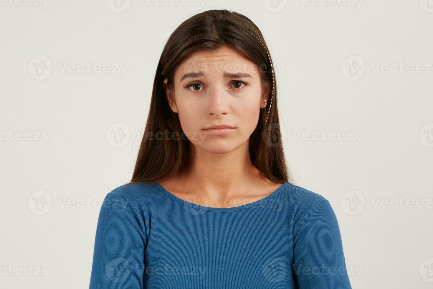 fechar-se do triste chateado jovem mulher com grandes cabelo desgasta marinha manga comprida parece depressivo e parece diretamente dentro Câmera isolado sobre branco fundo foto