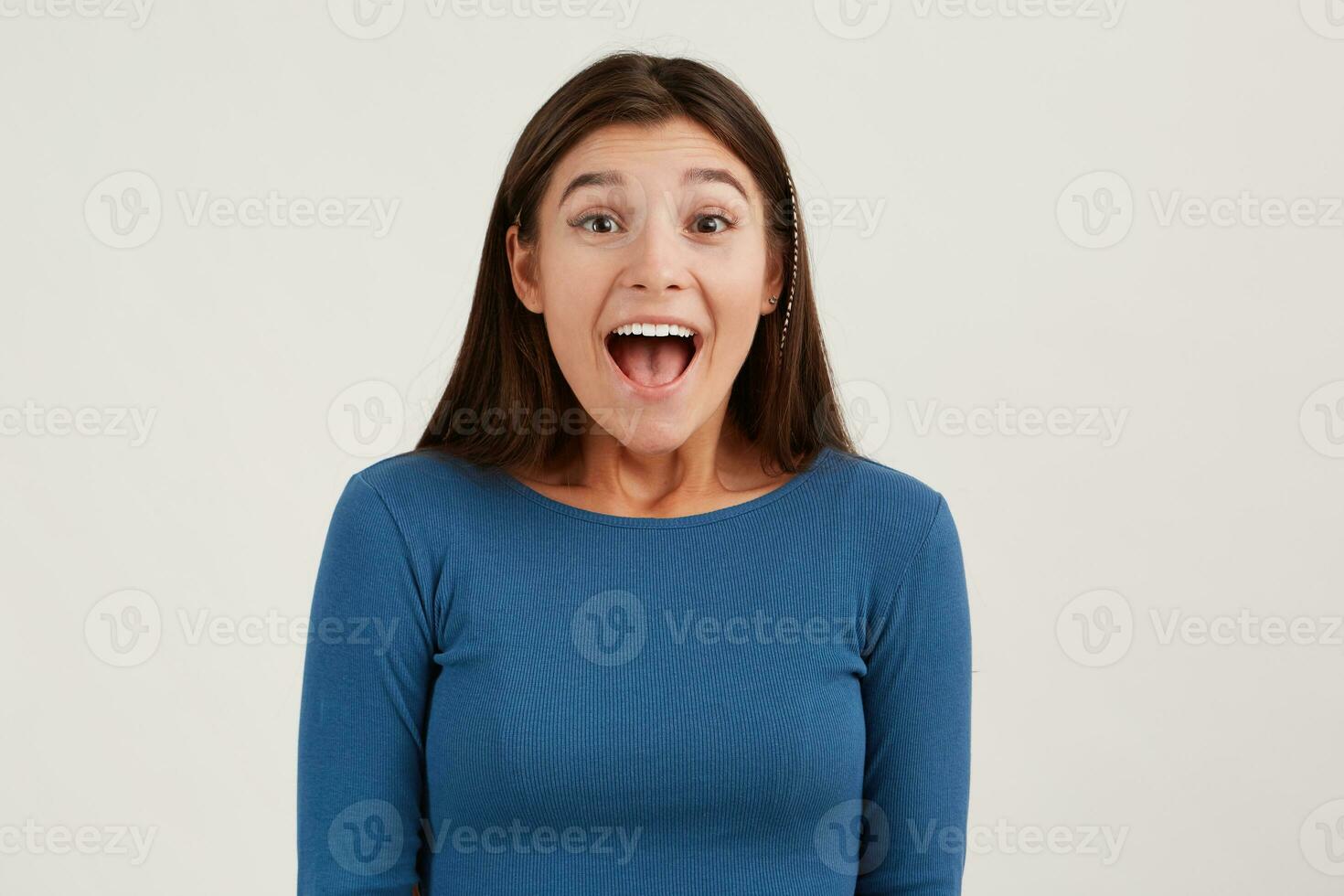 retrato do feliz animado jovem mulher com grandes cabelo e aberto boca desgasta marinha manga comprida parece surpreso e gritando isolado sobre branco fundo foto