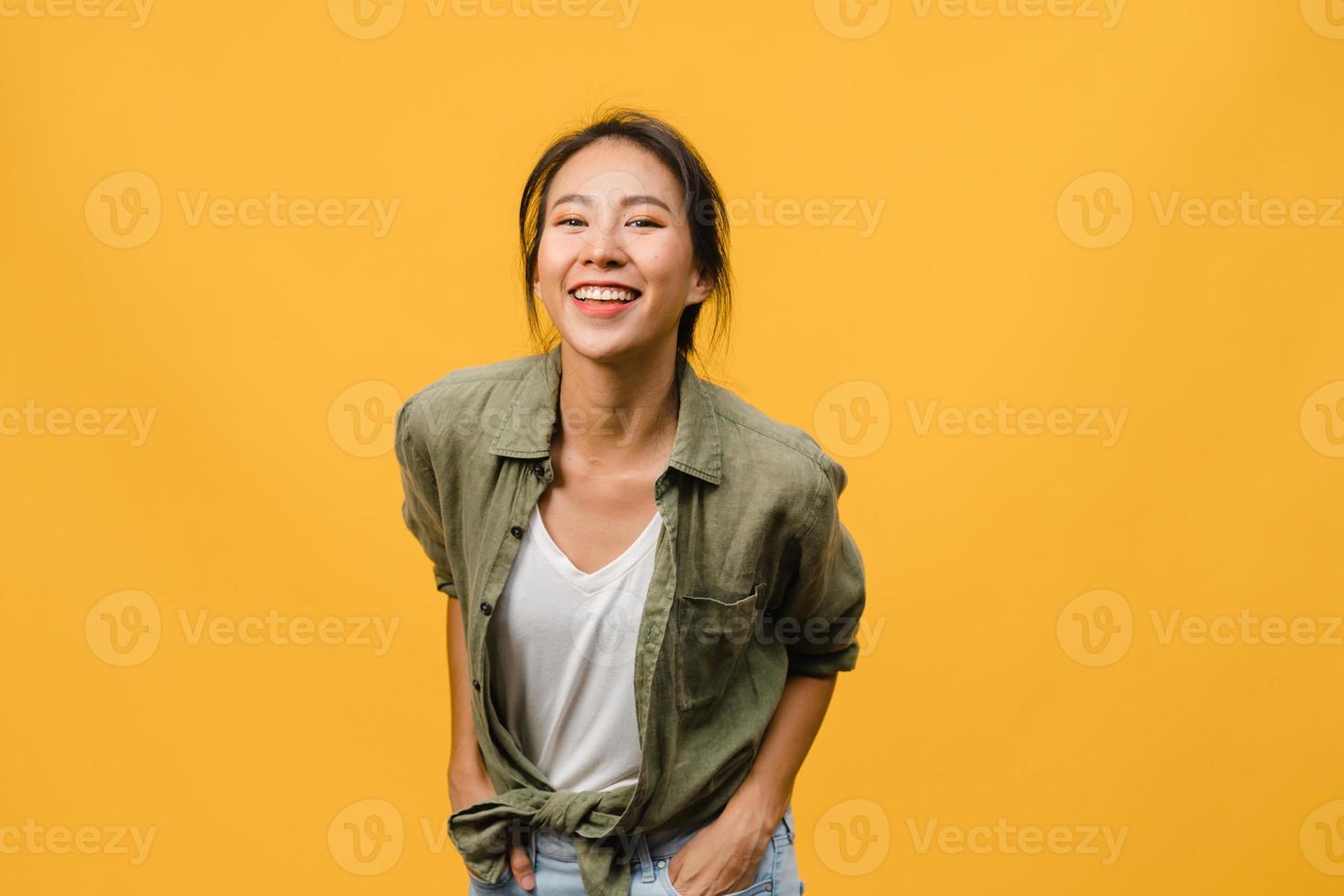 jovem asiática com expressão positiva, sorriso largo, vestida com roupas casuais e olhando para a câmera sobre fundo amarelo. feliz adorável feliz mulher alegra sucesso. conceito de expressão facial. foto