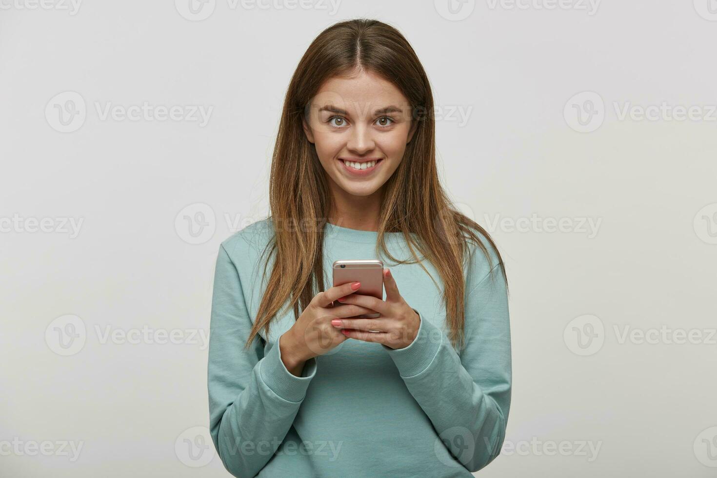 bonita menina segurando Móvel telefone e ouvindo música. música amante conceito. lindo fêmea vestindo casual azul grandes manga camiseta, Selecione% s música dentro jogar lista, conversando, sobre branco fundo foto