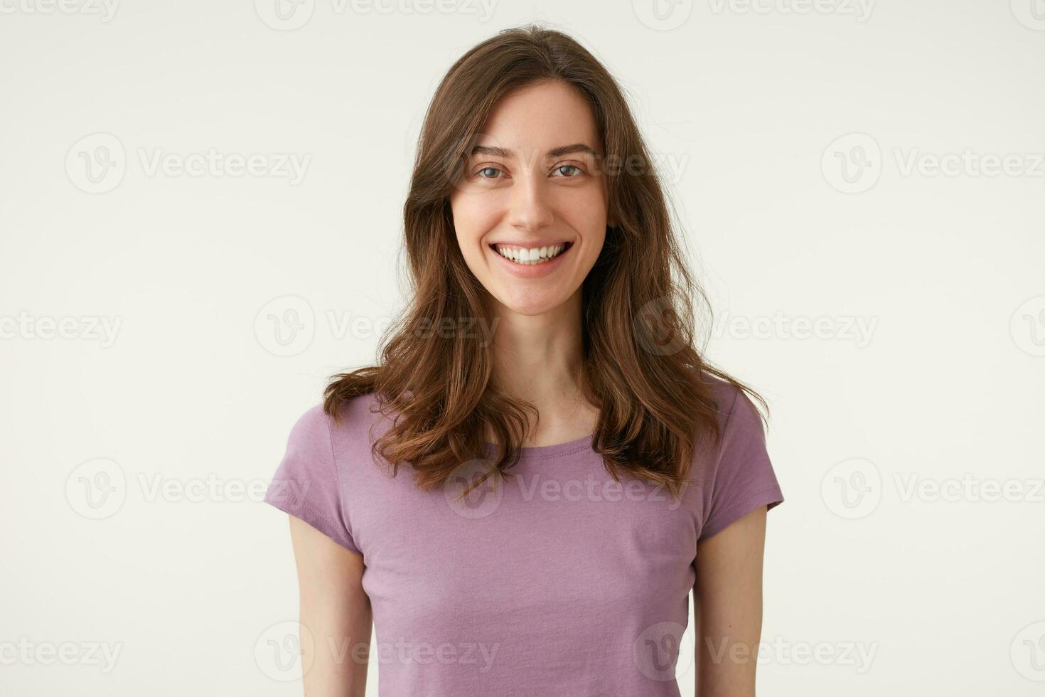 Tiros na Cabeça do agradável atraente jovem senhora, agradavelmente sorridente olhando diretamente Câmera, desgasta tolet camiseta, isolado em uma branco fundo dentro estúdio. foto