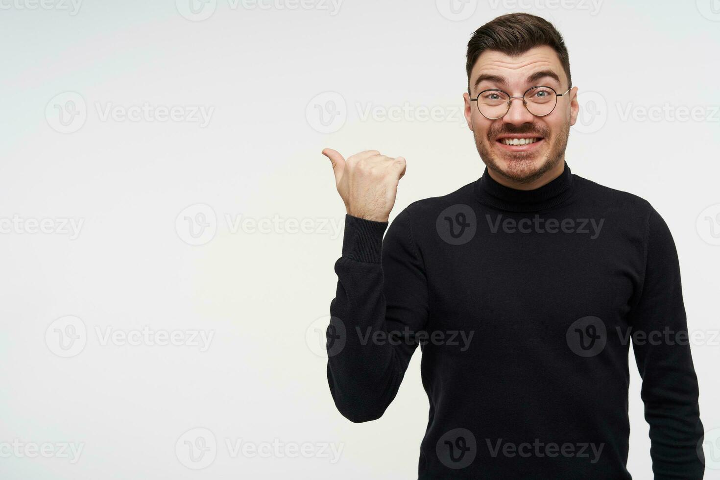 alegre jovem adorável curto cabelos barbudo morena cara apontando a parte, de lado com elevado mão e olhando alegremente às Câmera com Largo sorriso, posando sobre branco fundo foto